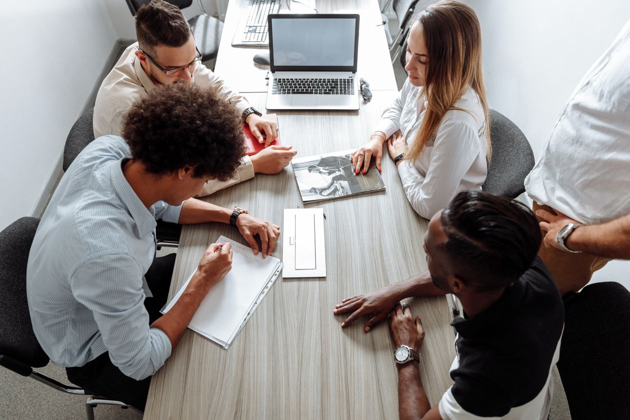 Four colleagues reviewing documents and a laptop around a conference table