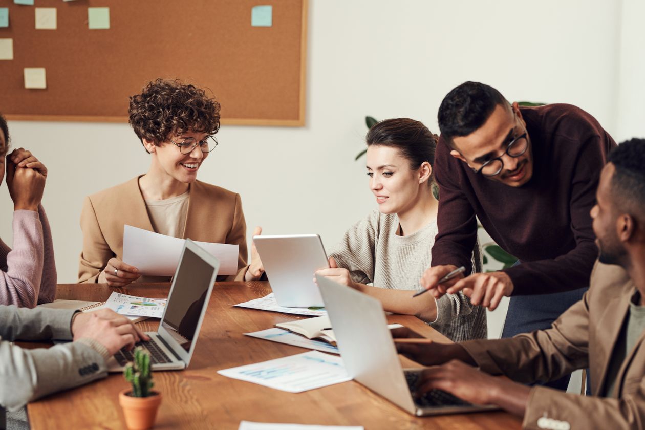 A small team working together around a table with laptops and notes