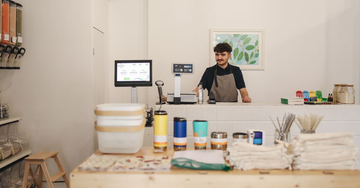 A small shop owner standing behind the counter of his store